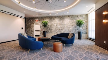 A modern lounge area with blue sofas, a coffee table, and a stone accent wall.