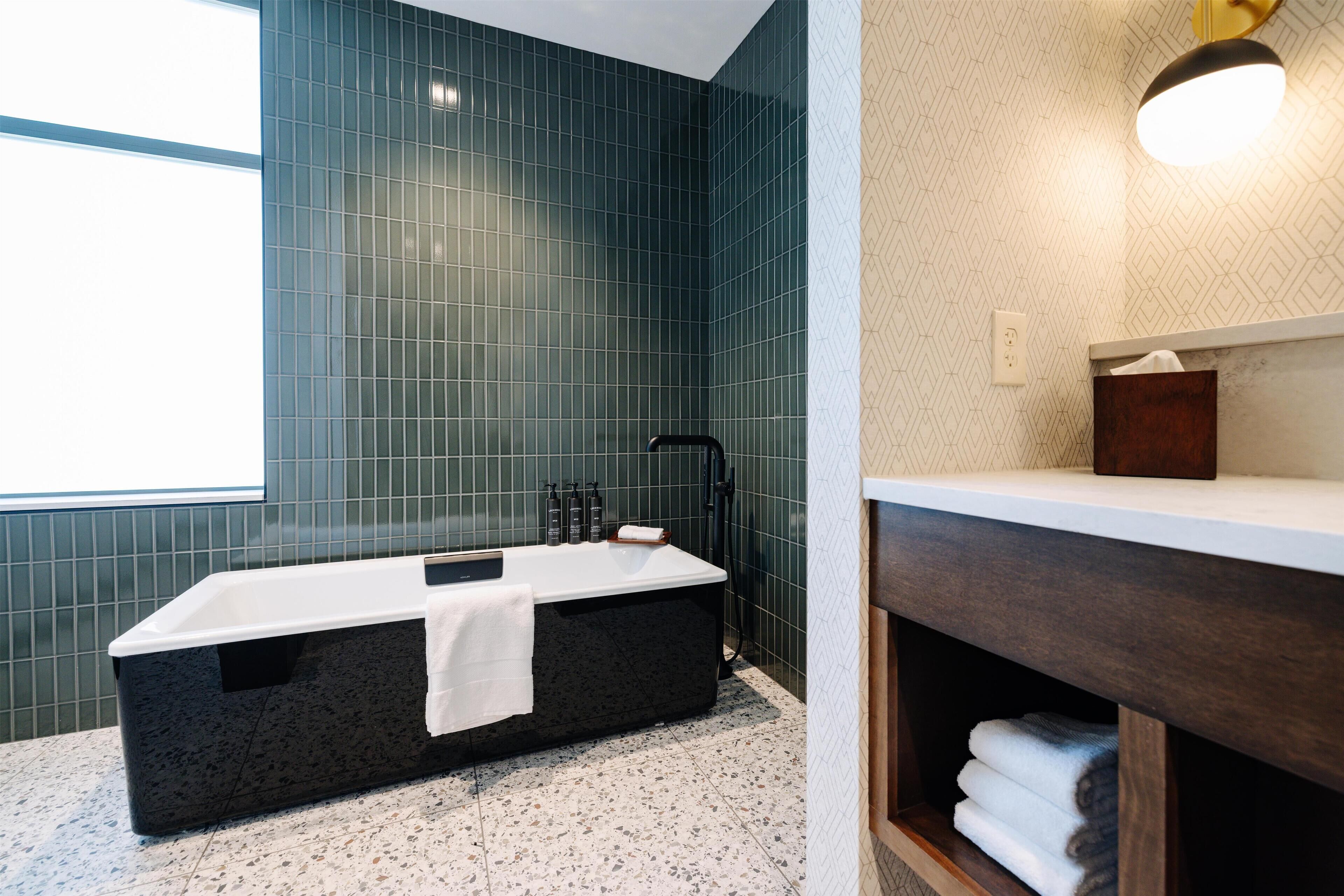 A modern bathroom with a freestanding bathtub, a vanity with a mirror, and a towel rack.