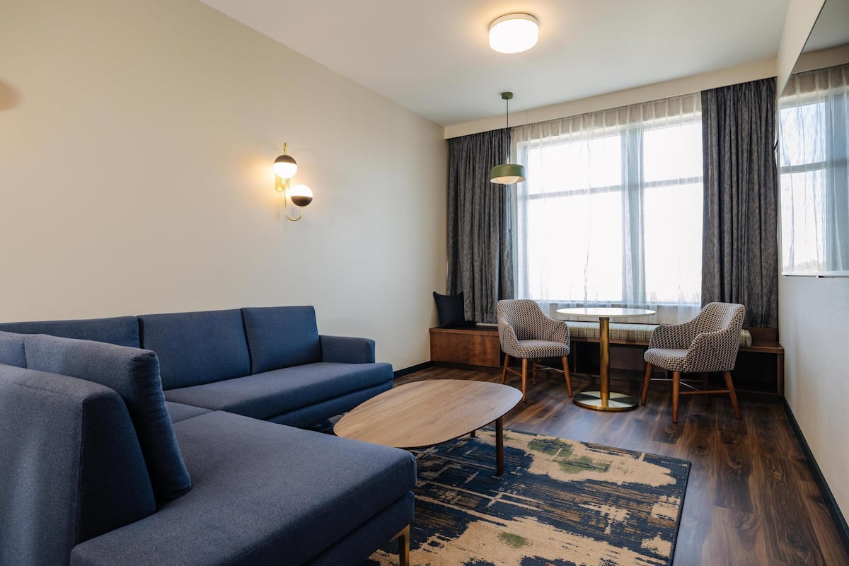 A modern living room with a blue sofa, a round coffee table, and a dining area with a small table and chairs.