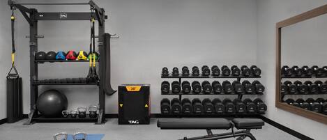 A gym with a squat rack, kettlebells, a bench, and a wall of dumbbells.