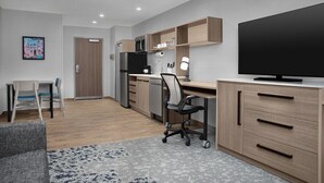 Una cocina moderna con microondas, estufa y armarios, un comedor con mesa y sillas, y un televisor en la pared.