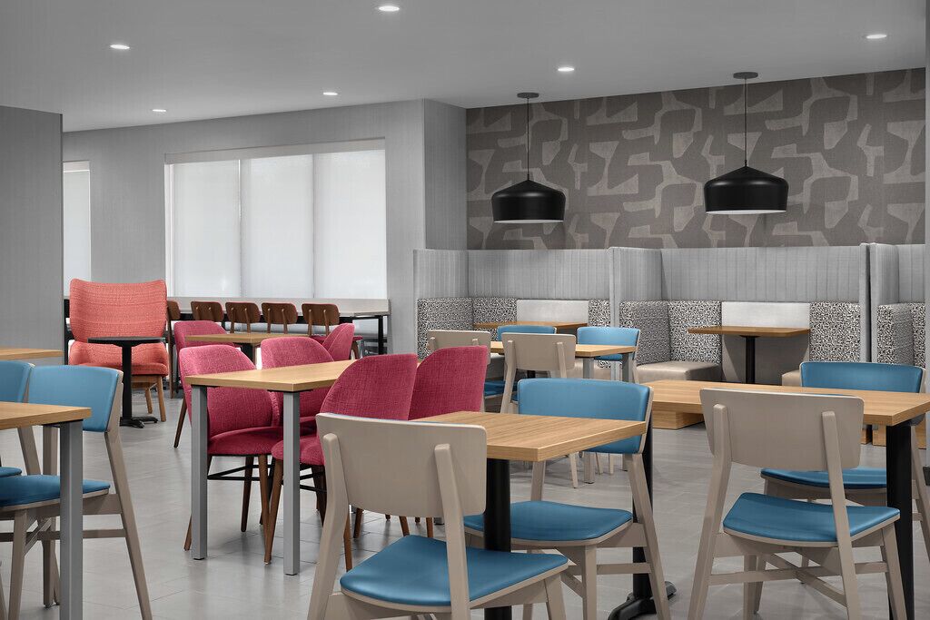 A modern dining area with tables and chairs, a patterned wall, and pendant lighting.