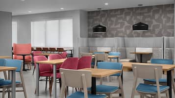 A modern dining area with tables and chairs, a patterned wall, and pendant lighting.