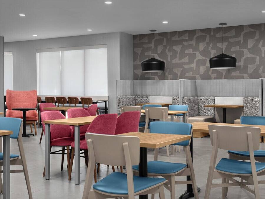 A modern dining area with tables and chairs, a patterned wall, and pendant lighting.