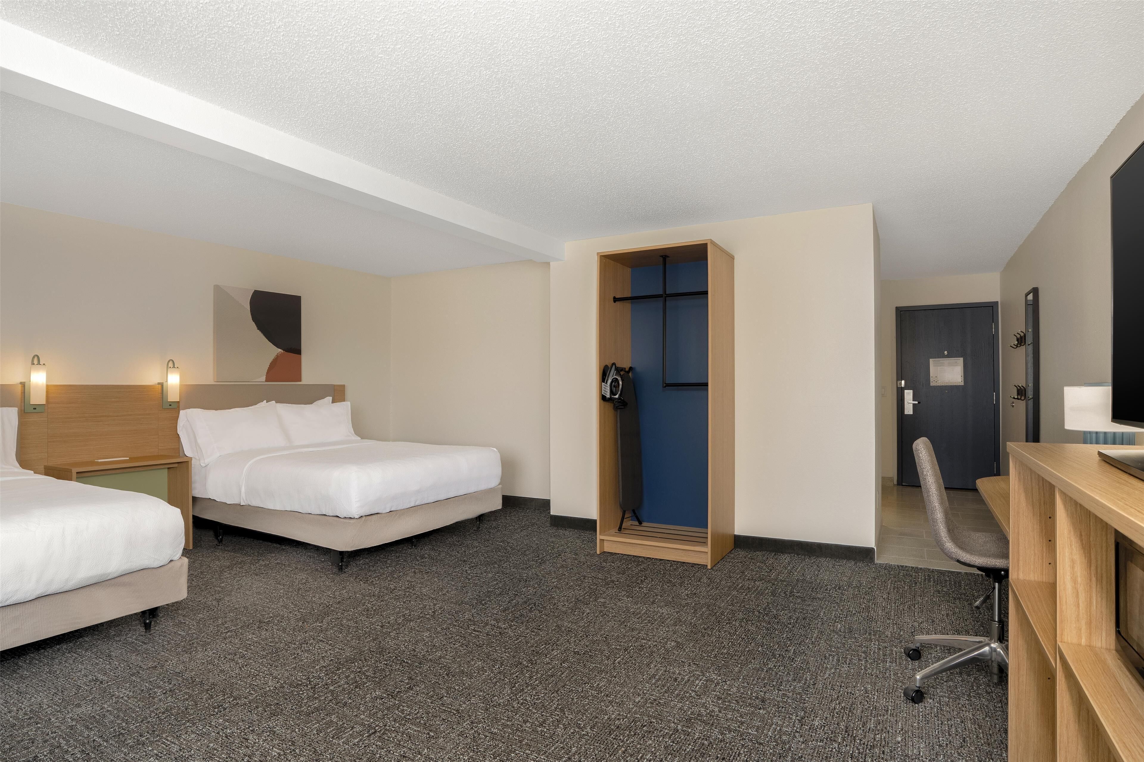 A hotel room with two beds, a desk, and a wardrobe.