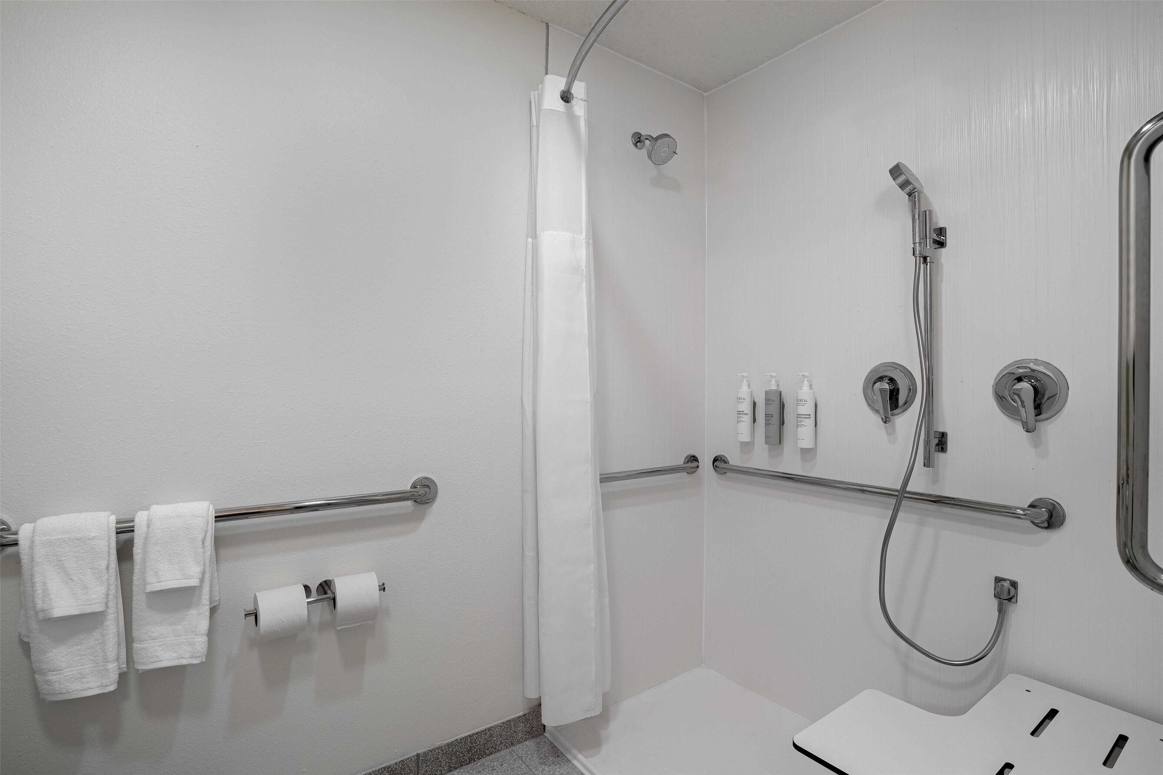 Un baño moderno con ducha, papel higiénico y jabón de manos.