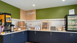A modern kitchen with a coffee machine, bread display, and a refrigerator. - Spark By Hilton Carlisle South (Carlisle)