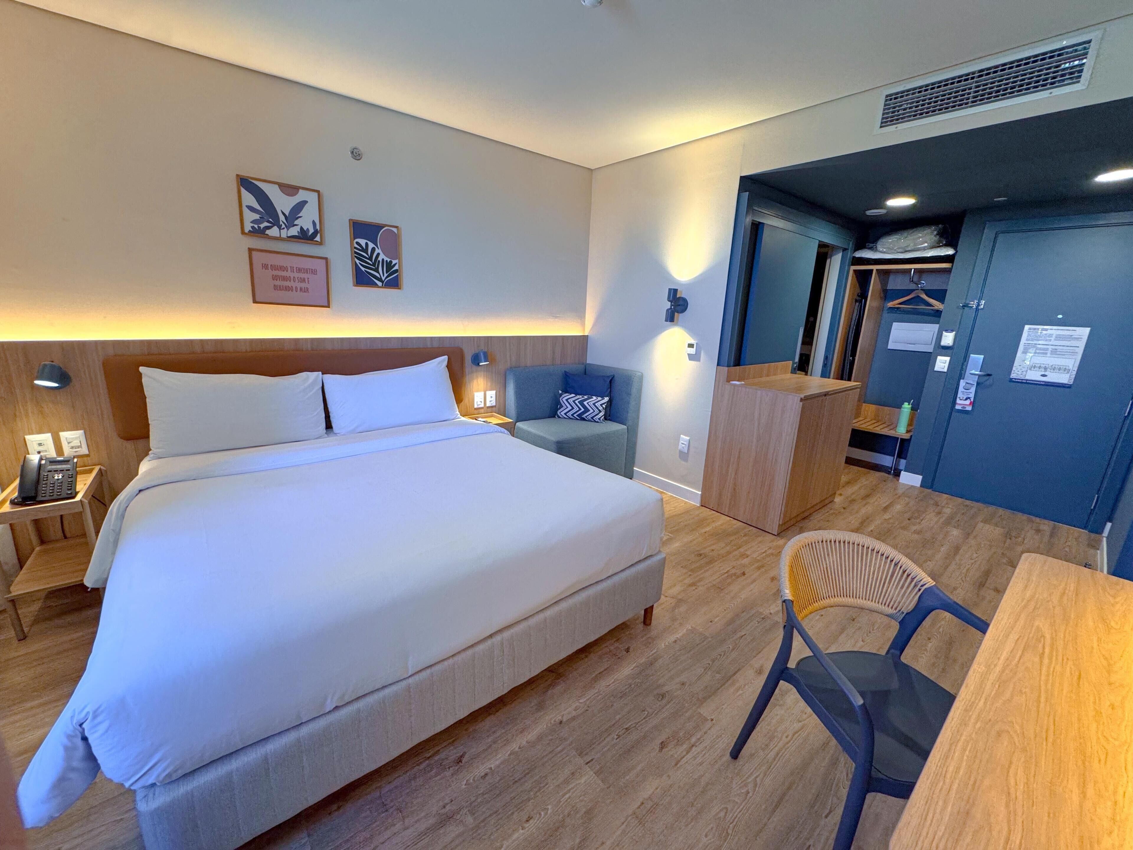 Ett hotellrum med en stor säng, sängbord, ett skrivbord, en stol och en garderob.