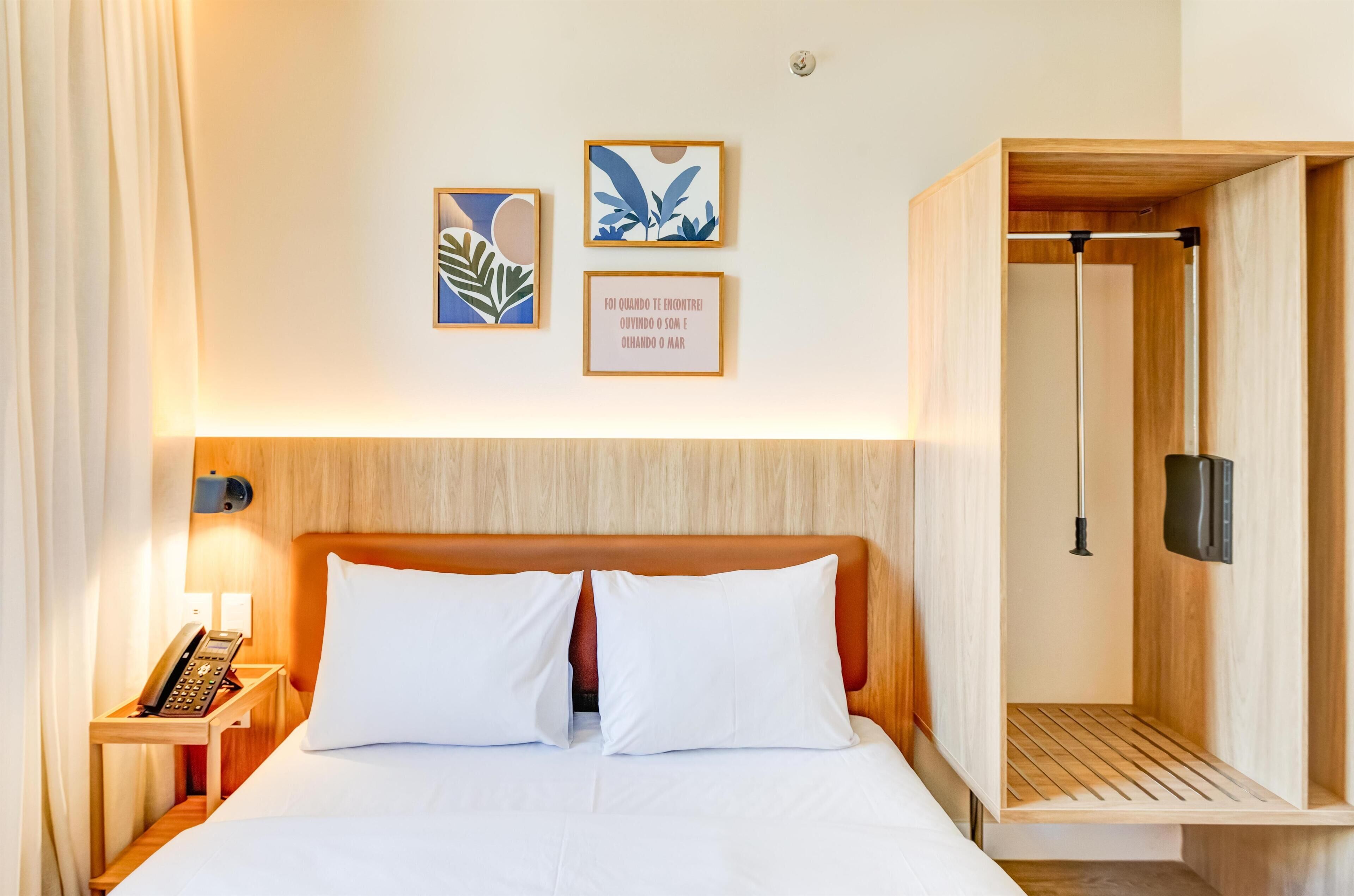 Habitación de hotel con cama, teléfono auxiliar y cabecero de madera.