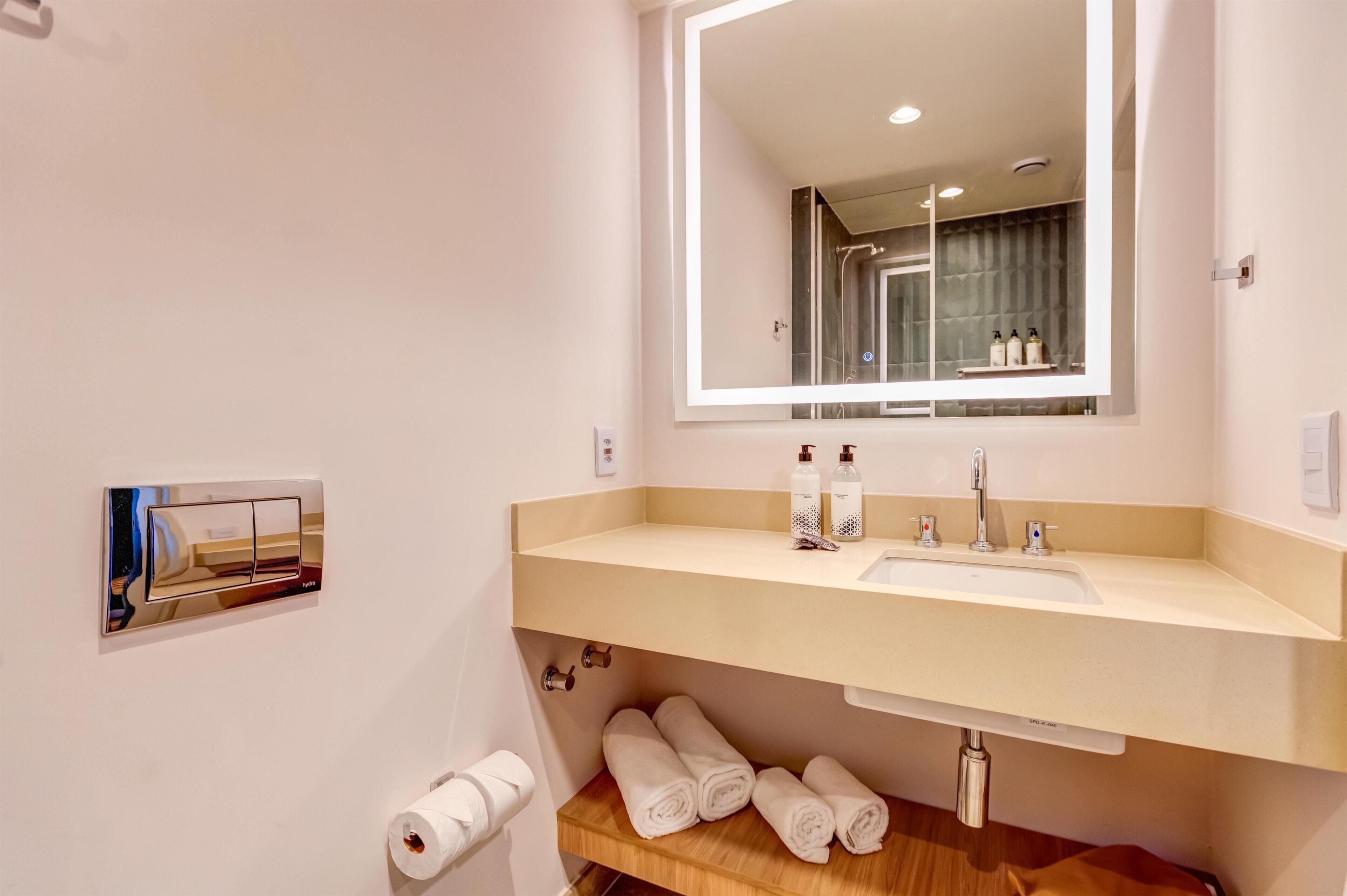 A bathroom with a large mirror, a sink, and a towel rack.