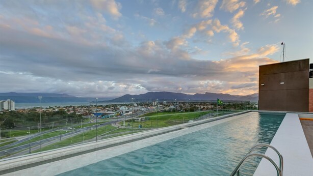 A swimming pool with a view of a cityscape and mountains in the background. - Hampton By Hilton Caraguatatuba Serramar (Caraguatatuba)