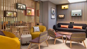 Un salon moderne comprenant un canapé d’angle, des fauteuils, une table basse et un élément de séparation décoratif doté d’étagères.