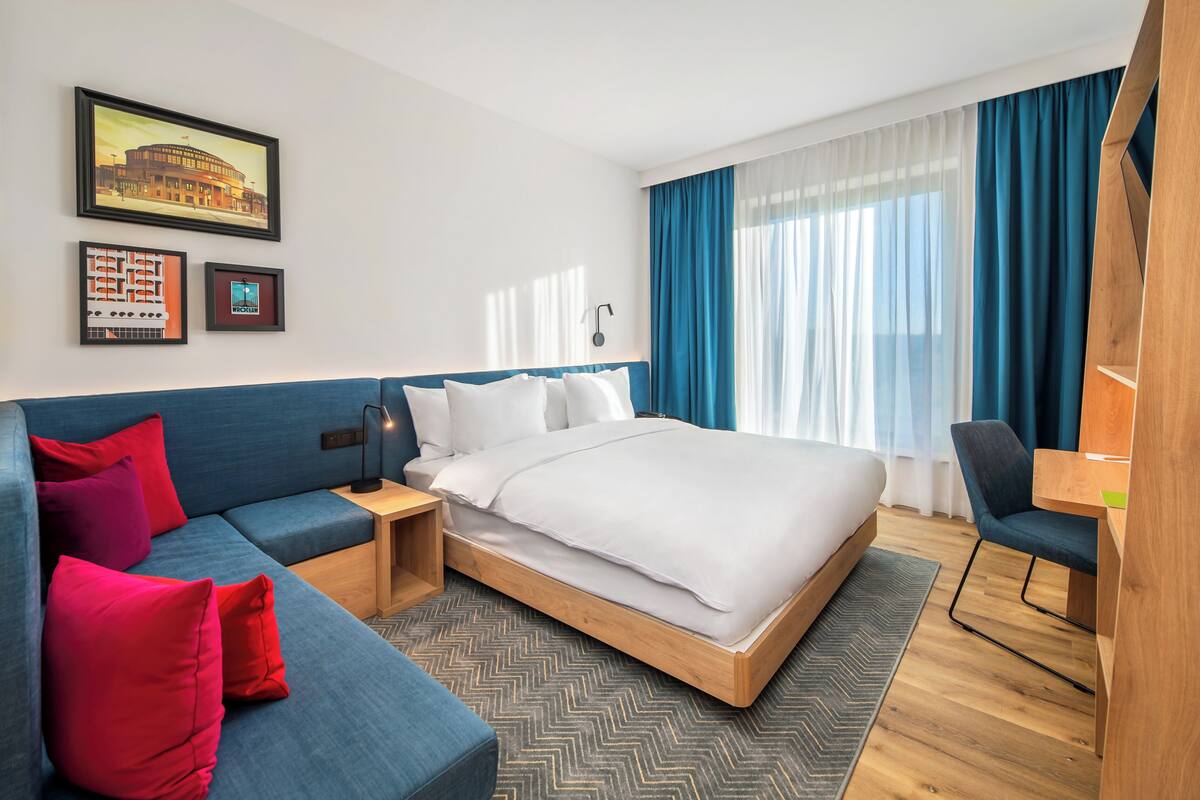 Ett hotellrum med en säng, en soffa, ett skrivbord och en stol.