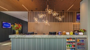 Un espace d’accueil d’hôtel avec un comptoir en marbre, un réfrigérateur rempli de collations et un panneau indiquant le nom de l’hôtel.