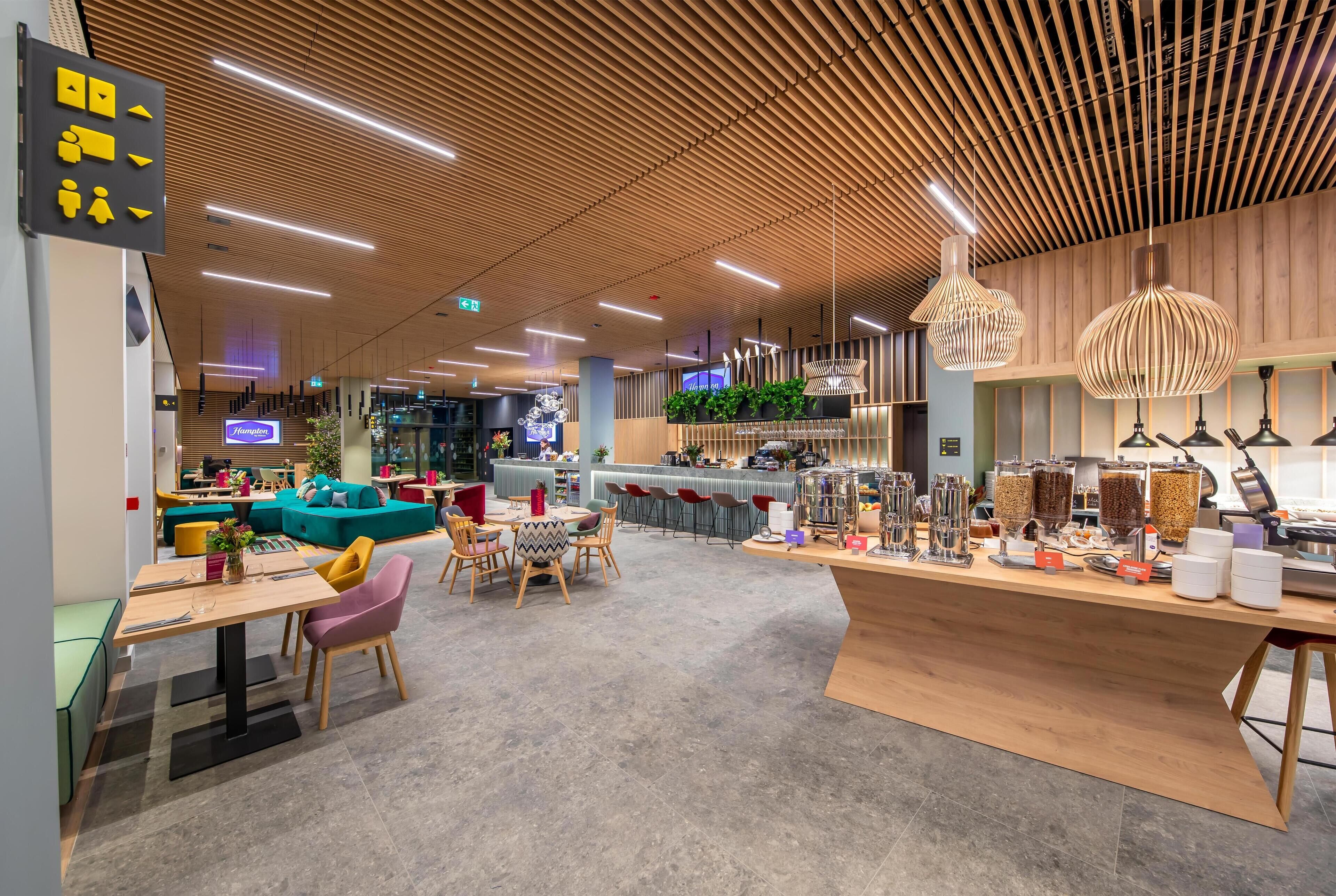 Una cafetería moderna con techo de madera, zona de estar y mostrador con diversos productos.