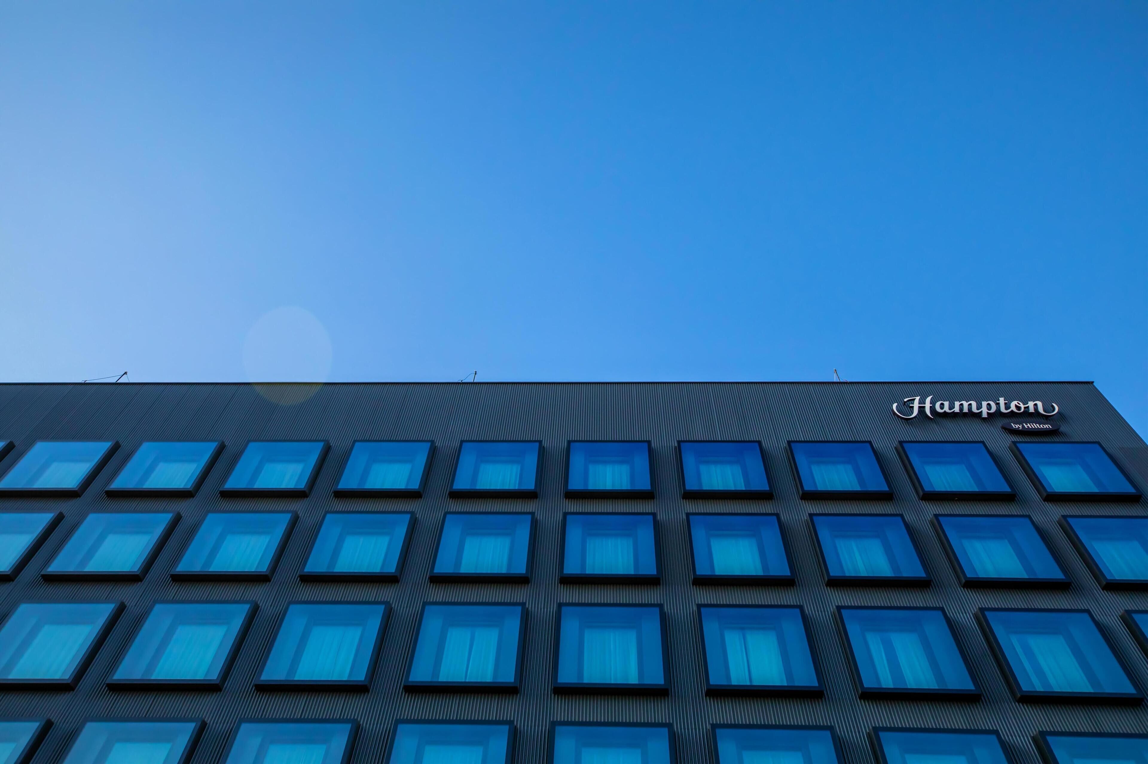 A modern building with a grid of windows and the name "Hampton" on the facade.