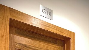Une porte en bois avec une plaque métallique portant l’inscription « G14 » et une poignée de porte moderne.