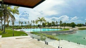 A pool area with clear water, surrounded by palm trees and a view of the sky.