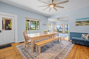 A spacious room with a wooden dining table, benches, a blue sofa, and a view of the outdoors.