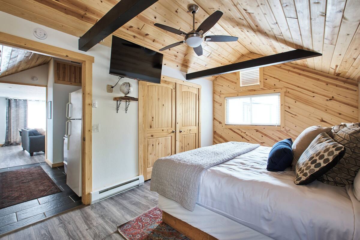 Una camera da letto con un letto, soffitto in legno e una ventola a soffitto.