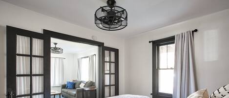 A bedroom with a bed, a large mirror, and a view of another room through an open door.