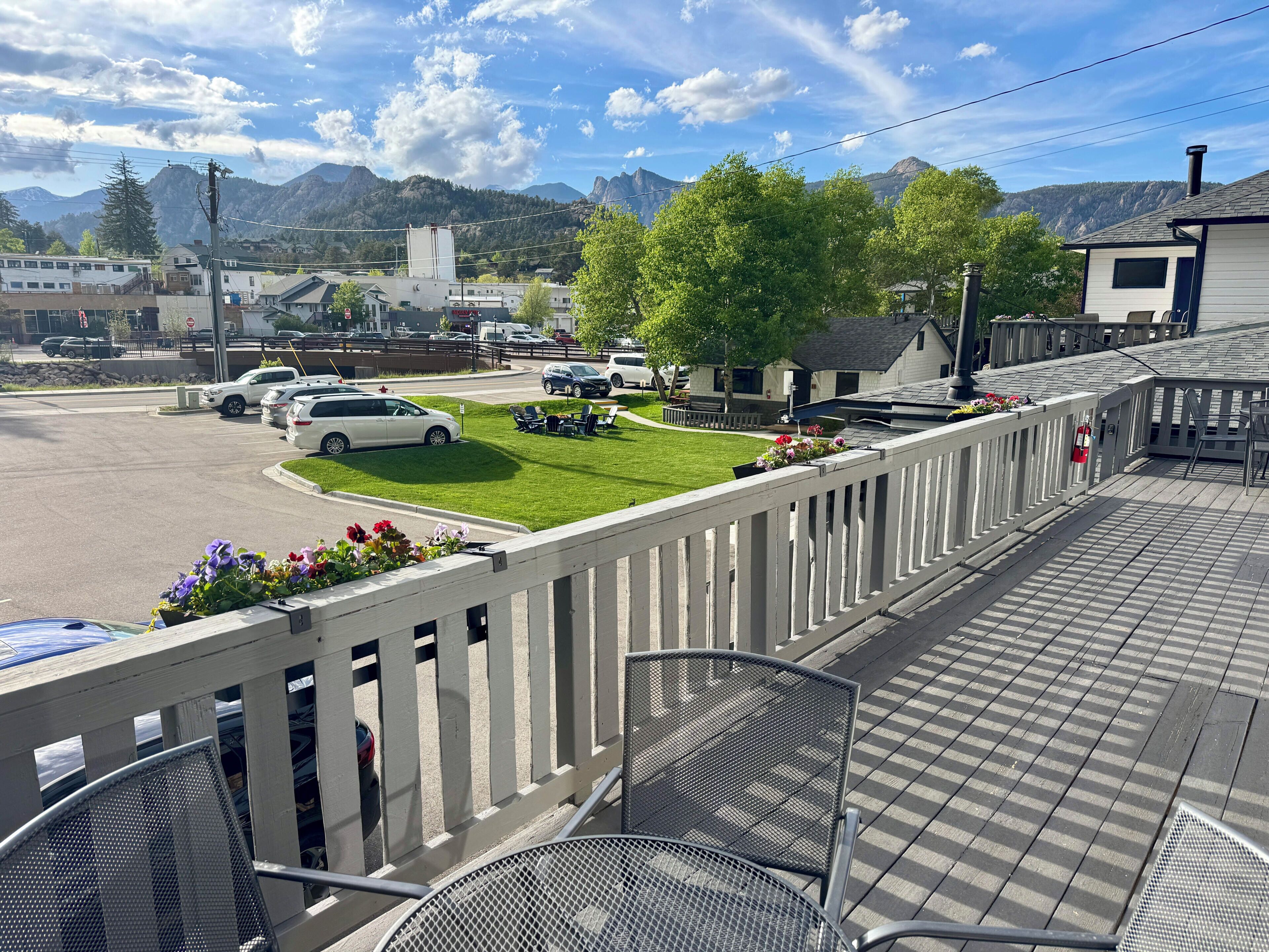 Ein Balkon mit Blick auf einen Parkplatz, eine Grünfläche und Berge im Hintergrund.