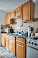 Una cocina con armarios de madera, microondas, fregadero y estufa.