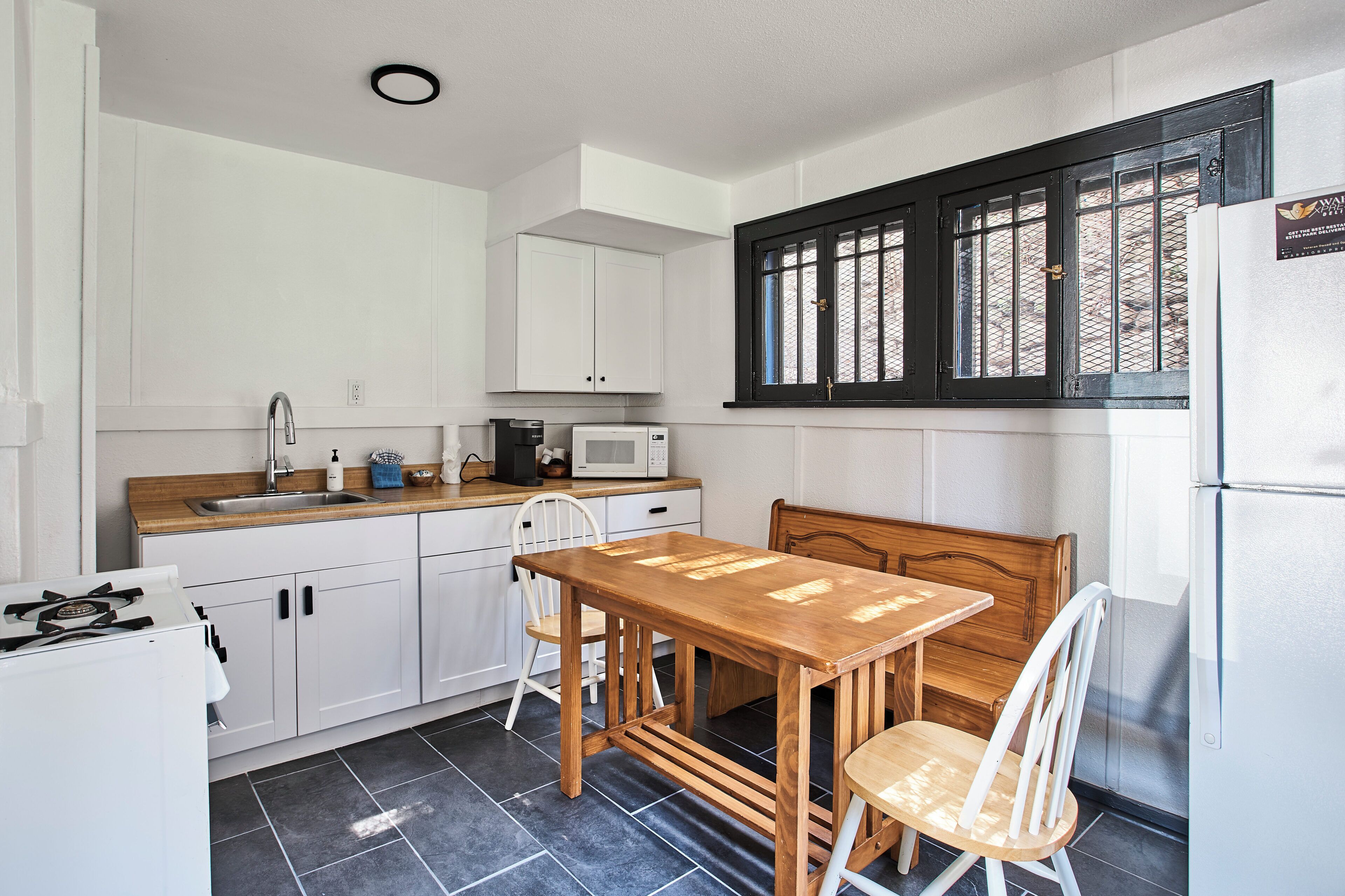 A compact kitchen with white cabinets, a wooden table, and a built-in microwave.