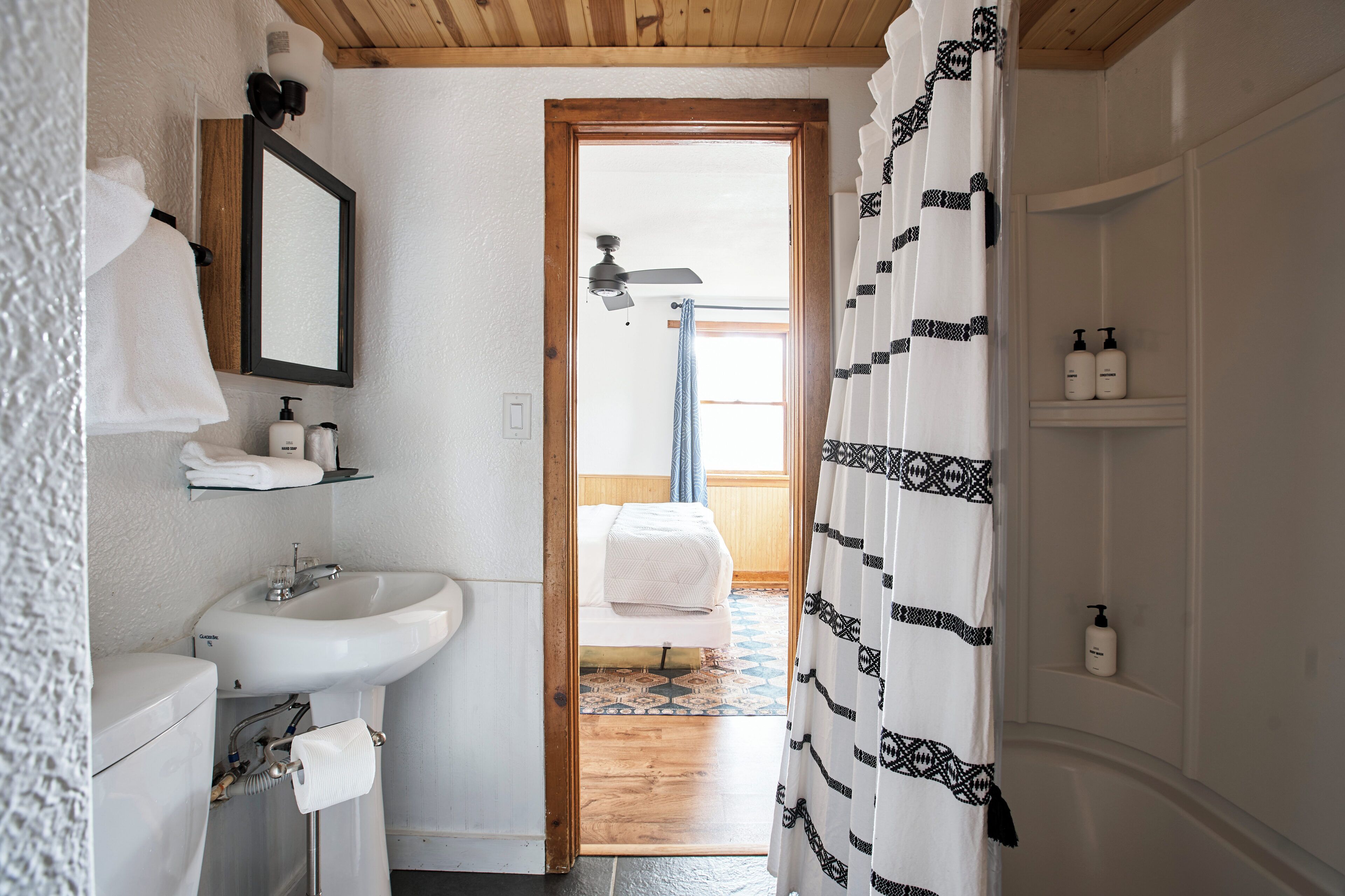A bathroom with a sink, mirror, and shower curtain.