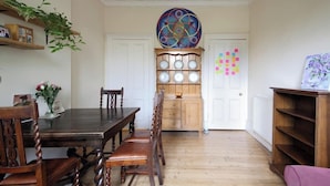 Une salle à manger avec une table et des chaises en bois, un élément décoratif mural et un buffet en bois contenant des assiettes.