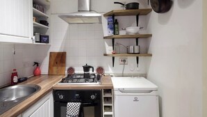 Une cuisine équipée d’une cuisinière à gaz, d’un four et d’un lave-vaisselle blanc.