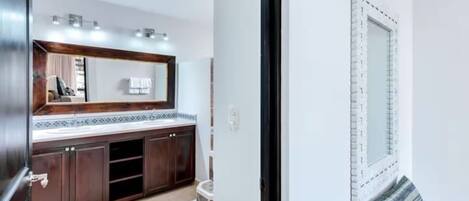 A modern bathroom with a large mirror, dark wooden cabinets, and a tiled floor.