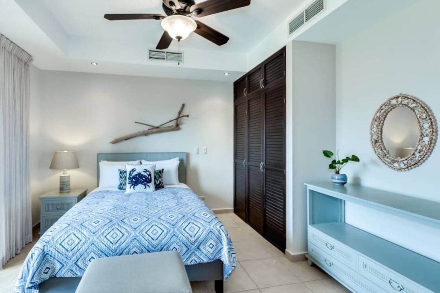 Ein Schlafzimmer mit Bett, Deckenventilator, Nachttisch, Kommode und Spiegel an der Wand.