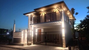A two-story house with a balcony, a gated entrance, and a well-lit exterior. - Luxury Solar Home where Style Meets Sustainability (Lipa)