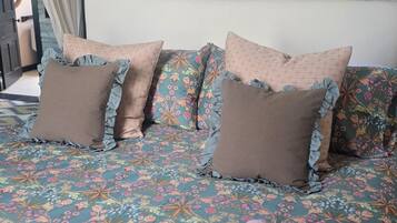 A bed with floral bedding, ruffled pillows, and a pink blanket.