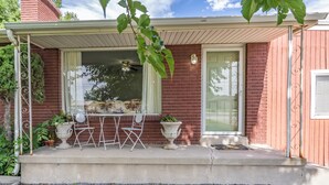 A house with a covered porch, a brick exterior, a sliding glass door, and outdoor furniture.