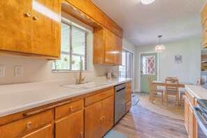 A kitchen with wooden cabinets, a stainless steel dishwasher, and a window.