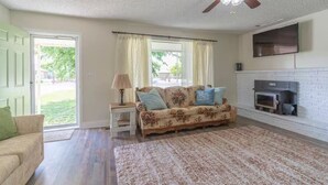 A living room with a sofa, a coffee table, a fireplace, and a ceiling fan.