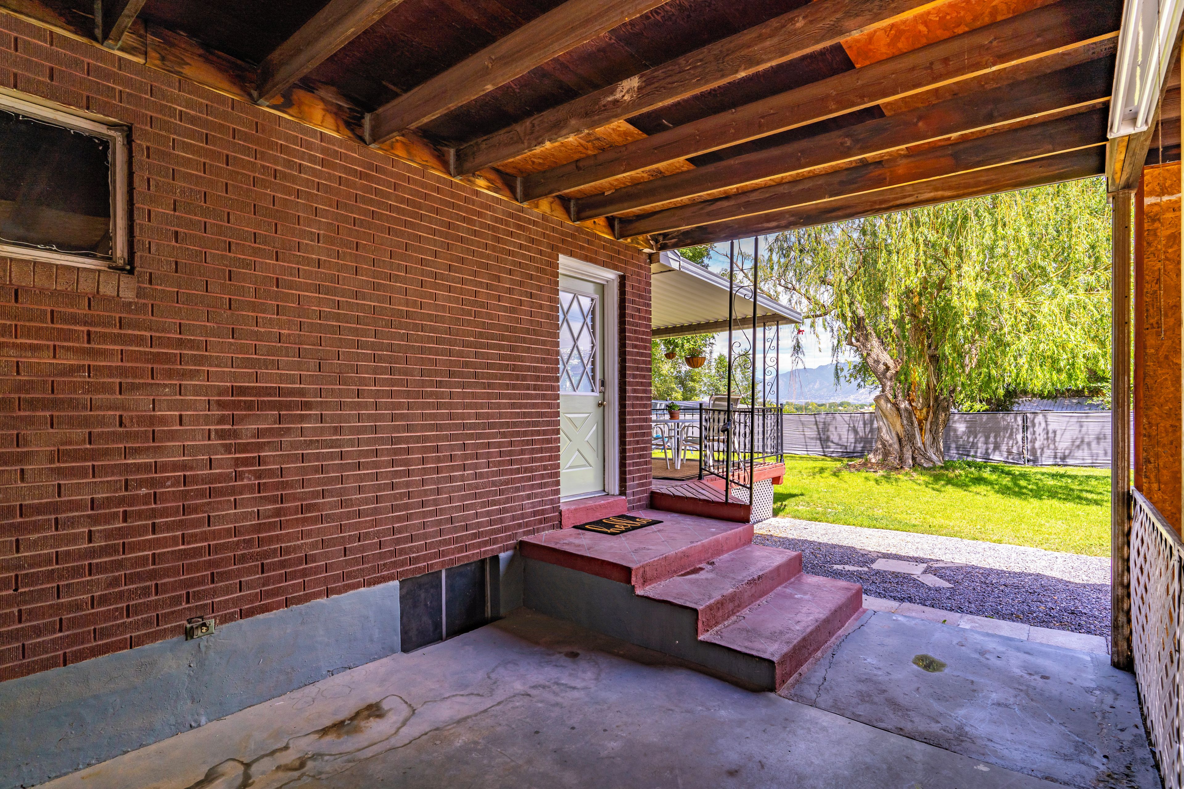 A brick building with a wooden ceiling, a door, and a small set of steps leading to a covered porch.