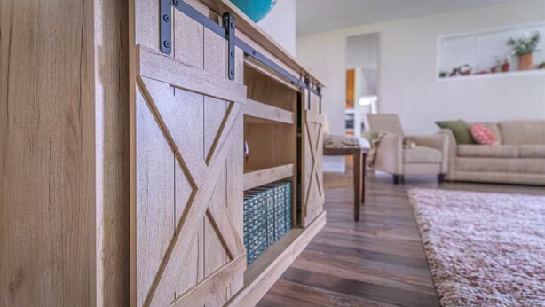 A wooden sliding barn door with a geometric pattern, a blue decorative item on top, and a patterned rug on the floor.