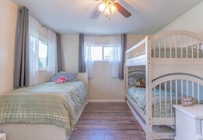 A child's bedroom with bunk beds, a ceiling fan, and a window with curtains. - Cowboy Ranch House (Taylorsville)