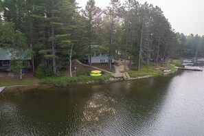 Una cabaña junto al lago con un muelle, rodeada de un bosque denso.