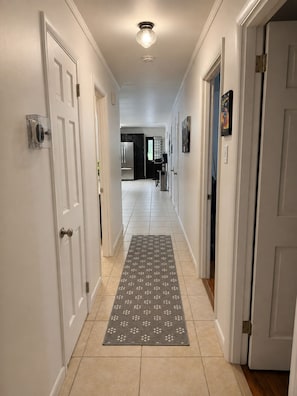 A hallway with white doors, a patterned rug, and a ceiling light.
