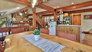 Una cocina amplia con vigas de madera, un comedor con una gran mesa de madera y una pared de piedra.