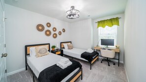 Une chambre avec deux lits, un bureau et un ordinateur.
