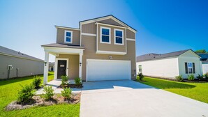 A two-story residential house with a garage, a front porch, and a well-maintained lawn.