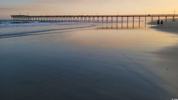 A beach with a pier extending into the water.