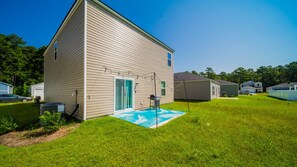 Une maison de plain-pied avec un jardin devant et un petit patio.