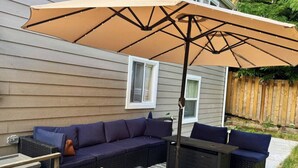 An outdoor seating area with a sectional sofa, a table, and an umbrella. - Modern 5BR 3BA Remodeled Home with BBQ Backyard (Seattle)
