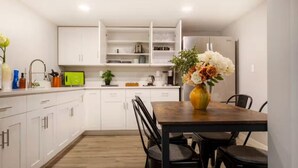 A modern kitchen with white cabinets, a wooden dining table, and a vase of flowers. - Modern Cozy Bright 2BR Lower Unit w/private entry (Seattle)